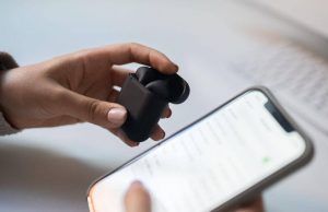 Une image d'écouteurs sans fil dans une main en connexion avec un iphone